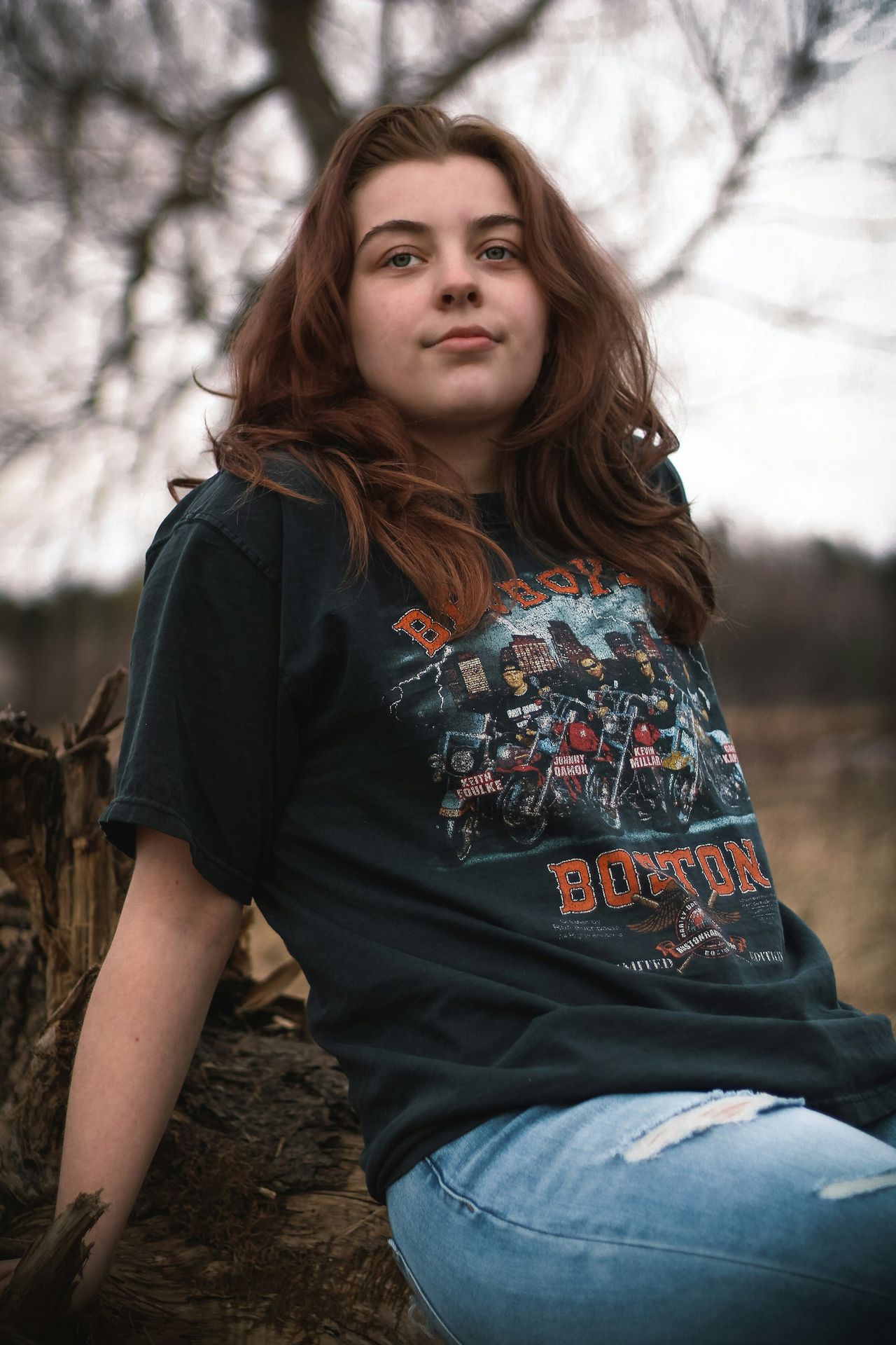 a woman sitting on a log in a field